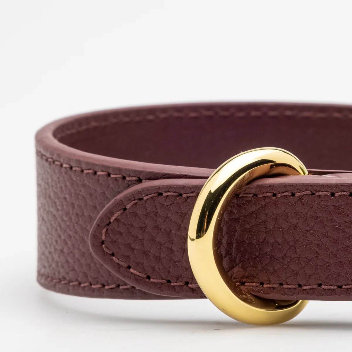 Close-up of the burgundy vegan leather dog collar by Collar of Sweden, showing gold ring and fine stitching – Gros plan sur le collier pour chien en cuir végan couleur bordeaux de Collar of Sweden avec anneau doré et coutures fines – Nahaufnahme des Hundehalsbands aus veganem Leder in der Farbe Burgunderrot von Collar of Sweden mit goldenem Ring und feiner Naht.