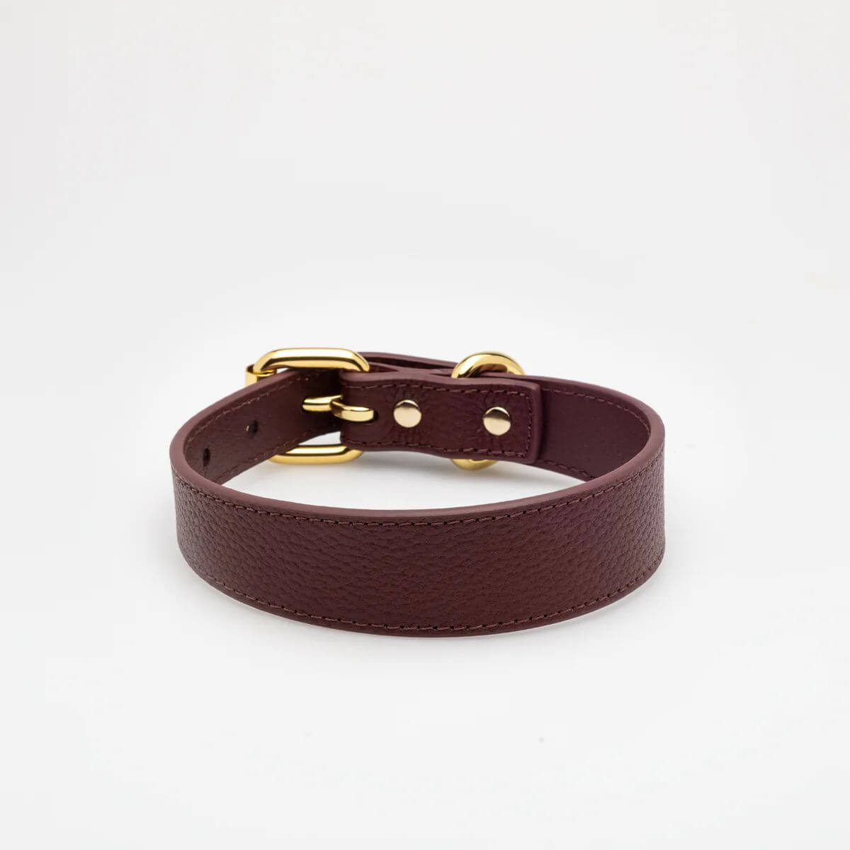 Angled view of the burgundy vegan leather dog collar by Collar of Sweden with gold buckle and detailed stitching – Vue en angle du collier pour chien en cuir végan couleur bordeaux de Collar of Sweden avec boucle dorée et coutures détaillées – Schräge Ansicht des Hundehalsbands aus burgunderrotem veganem Leder von Collar of Sweden mit goldener Schnalle und feiner Naht.