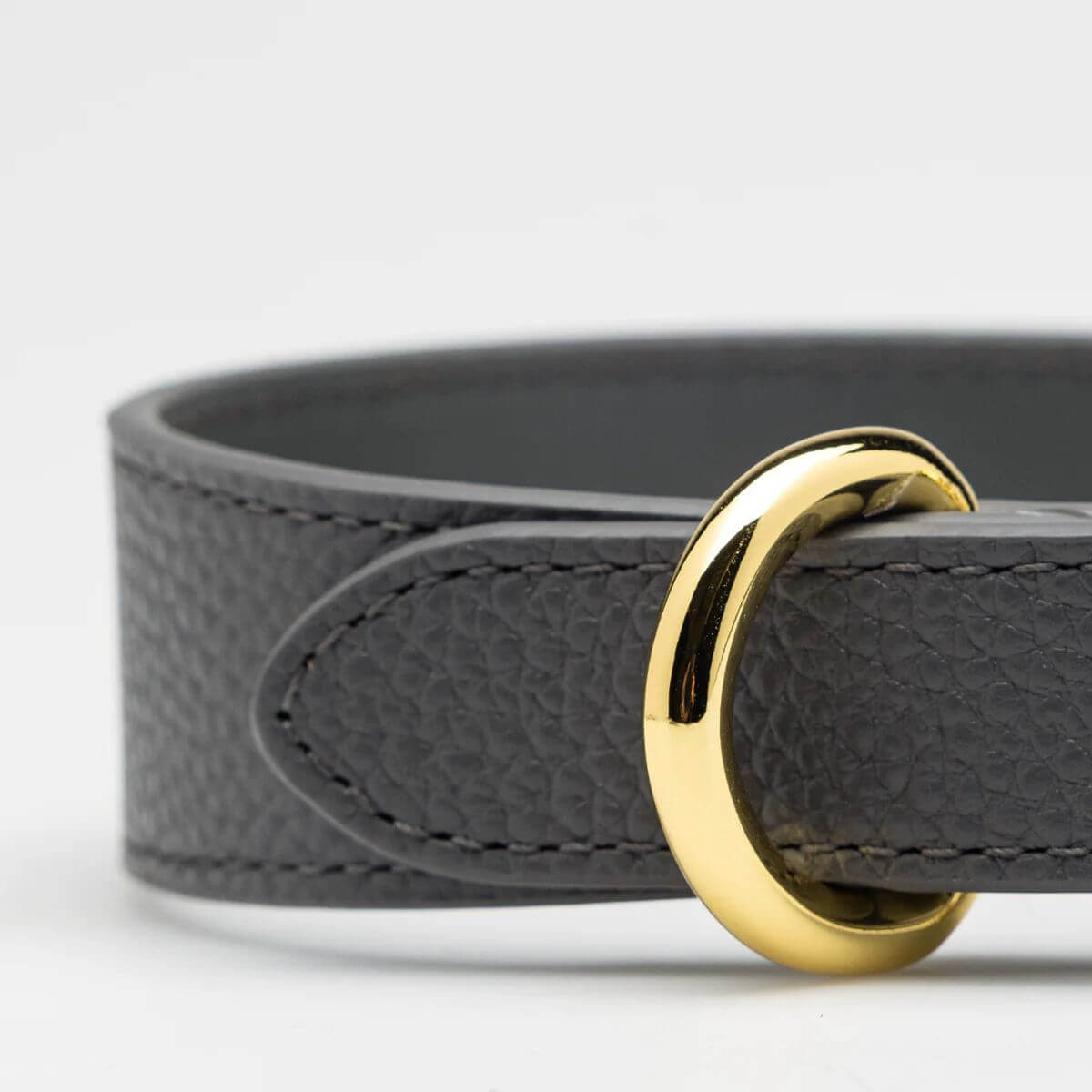 Close-up of the grey vegan leather dog collar by Collar of Sweden, showing gold ring and fine stitching – Gros plan sur le collier pour chien en cuir végan gris de Collar of Sweden avec anneau doré et coutures fines – Nahaufnahme des Hundehalsbands aus grauem veganem Leder von Collar of Sweden mit goldenem Ring und feiner Naht.