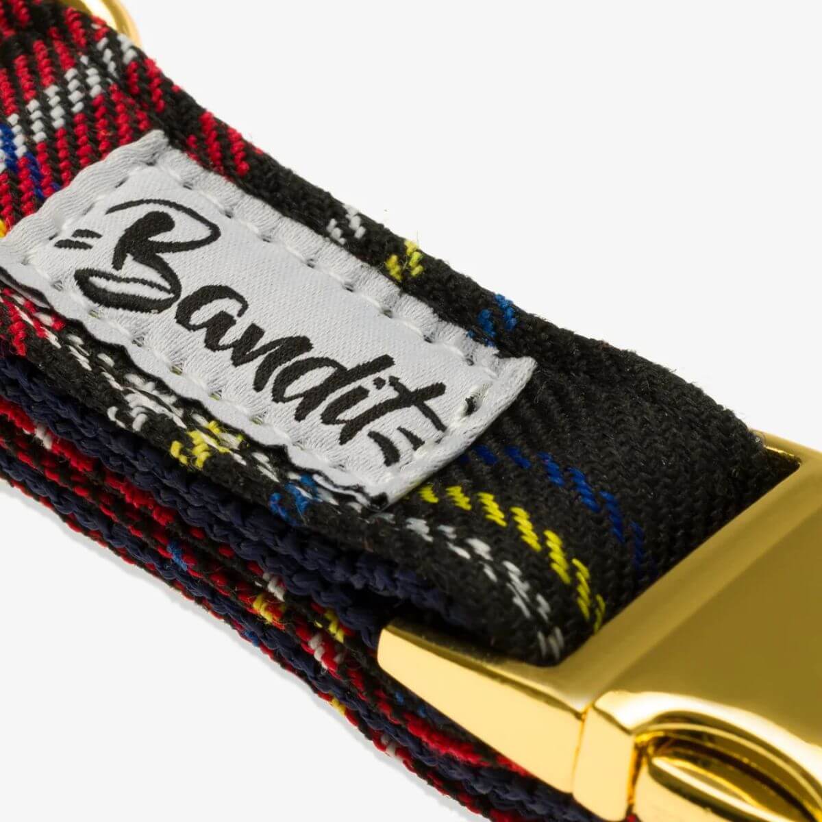Close-up of the French Bandit tartan plaid dog collar showcasing the brand label and detailed weave in red, blue, yellow, and black.
Gros plan sur le collier pour chien à motif écossais de la marque French Bandit, mettant en valeur l’étiquette de la marque et le tissu détaillé rouge, bleu, jaune et noir.
Nahaufnahme des karierten Hundehalsbands von French Bandit mit Markenetikett und feinem Stoffmuster in Rot, Blau, Gelb und Schwarz.