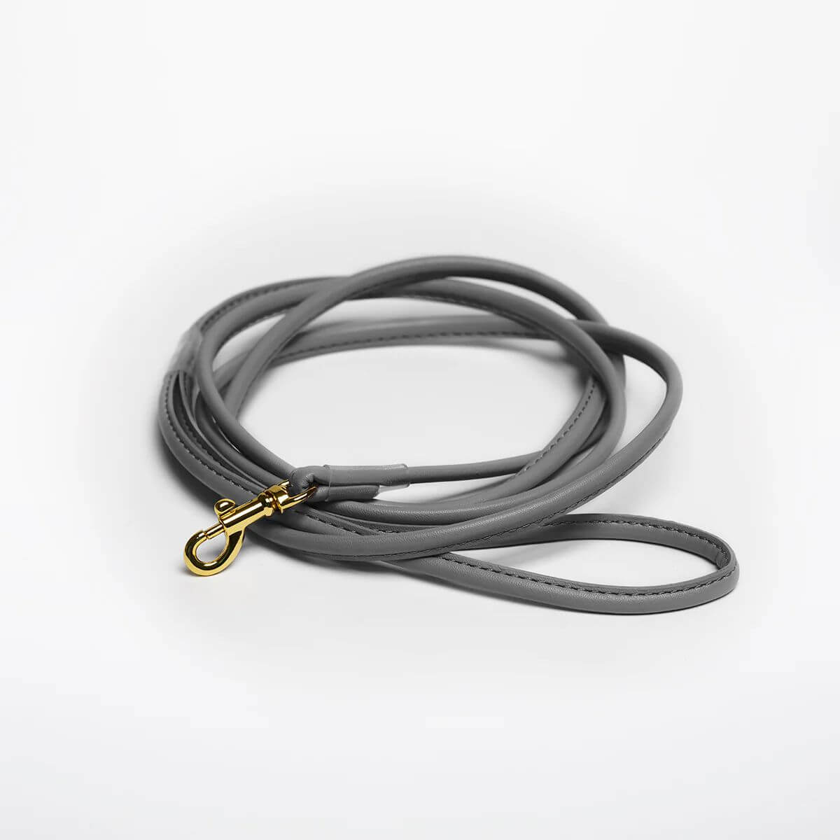 Grey vegan leather dog leash with gold snap hook by Collar of Sweden – Laisse pour chien en cuir végan gris avec mousqueton doré, signée Collar of Sweden – Hundeleine aus grauem veganem Leder mit goldenem Karabinerhaken von Collar of Sweden.