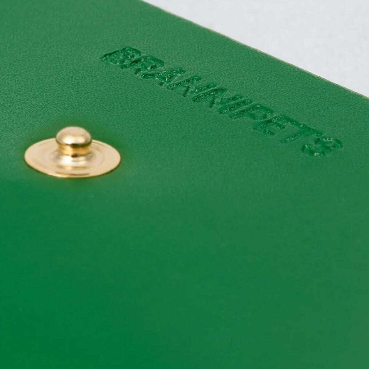 This image highlights the functional grommet of the Branni Pets green leather poop bag holder with a black bag ready for use. Dieses Bild zeigt die praktische Öse des Branni Pets Kotbeutelhalters aus grünem Leder mit einem einsatzbereiten schwarzen Beutel. Cette image met en valeur l'œillet fonctionnel du porte-sacs en cuir vert Branni Pets avec un sac noir prêt à l'emploi.