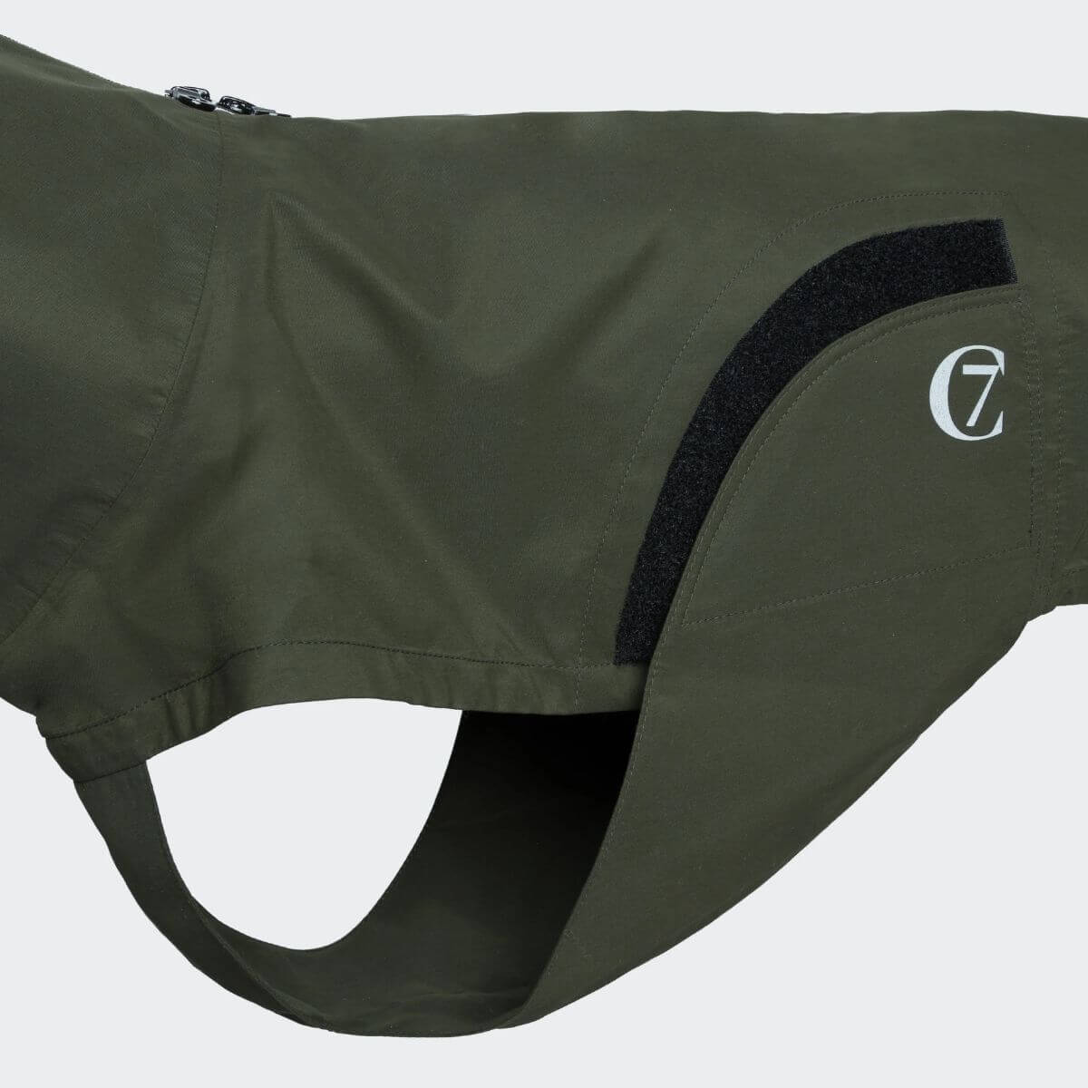 Close-up of the Cloud7 dog raincoat in olive green with velcro closure and logo on the side. / Nahaufnahme des Cloud7 Hunderegenmantels in Olivgrün mit Klettverschluss und seitlichem Logo. / Gros plan de l’imperméable pour chien Cloud7 en vert olive avec fermeture velcro et logo sur le côté.