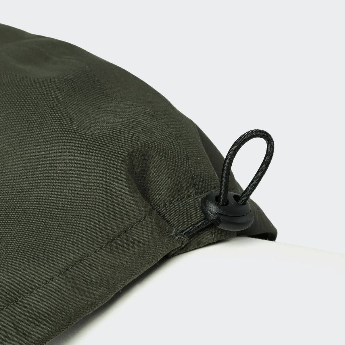 Detail view of the adjustable drawstring on the olive green Cloud7 dog raincoat. / Detailansicht des verstellbaren Kordelzugs am olivgrünen Hundemantel von Cloud7. / Détail du cordon réglable sur l’imperméable vert olive pour chien Cloud7.
