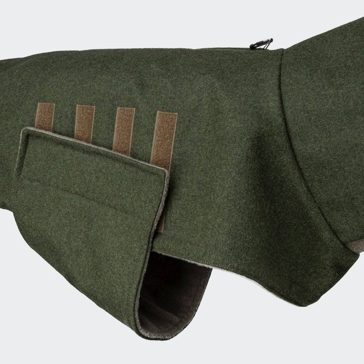 Close-up of side view showing velcro strap on Cloud7 green wool dog wintercoat. | Seitenansicht mit Klettverschluss am grünen Wollmantel von Cloud7. | Vue latérale avec sangle velcro sur le manteau en laine vert Cloud7.