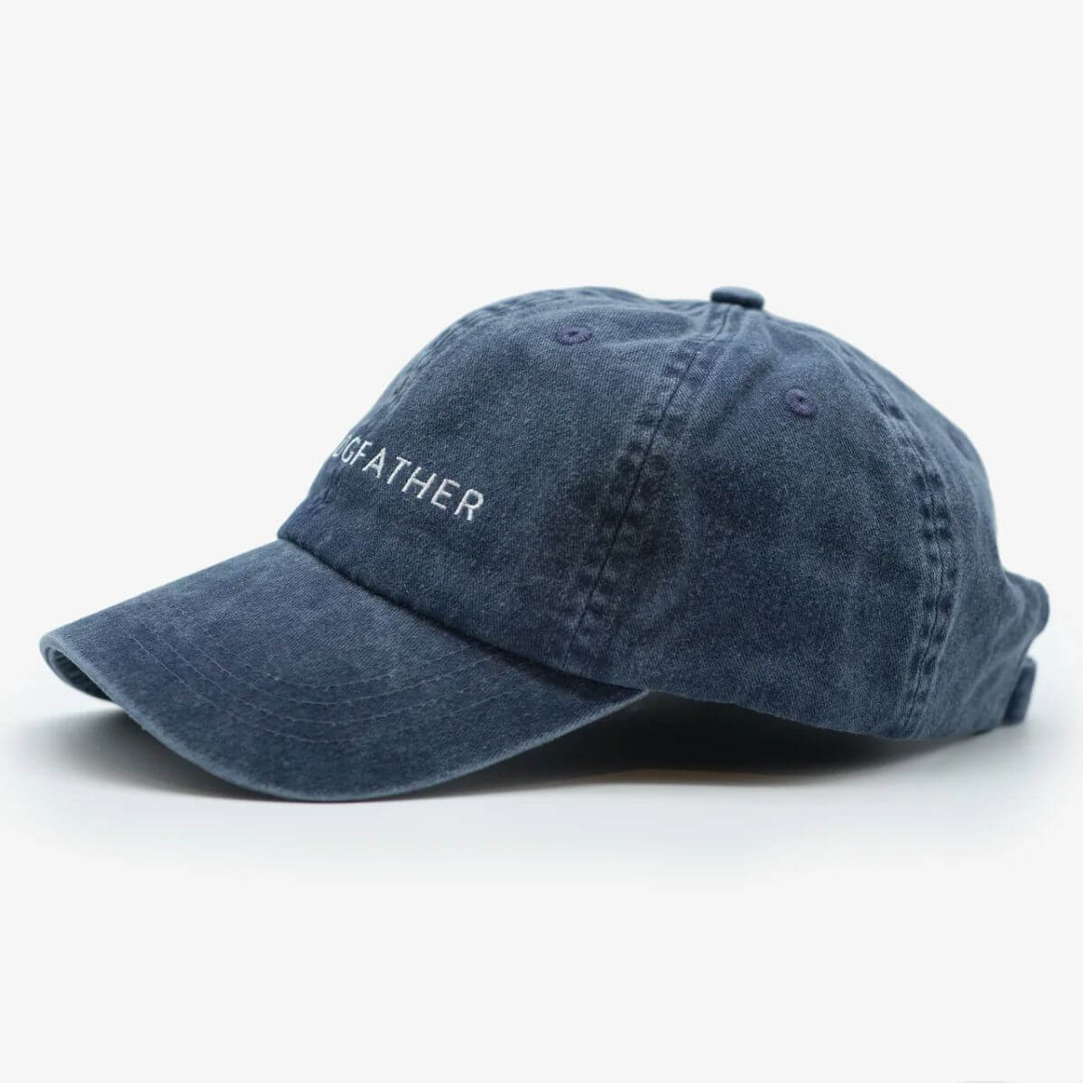 Side view of blue "THE DOGFATHER" baseball cap by Collar of Sweden in washed denim – Vue de côté de la casquette bleue "THE DOGFATHER" de Collar of Sweden en denim délavé – Seitenansicht der blaufarbenen „THE DOGFATHER“-Kappe von Collar of Sweden aus gewaschenem Denim.
