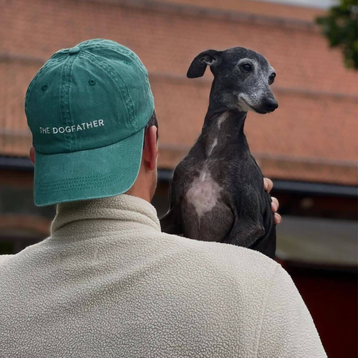 Man wearing a green washed denim baseball cap with "THE DOGFATHER" embroidered on the front by Collar of Sweden – Homme portant une casquette en denim vert délavé avec l'inscription "THE DOGFATHER" brodée à l'avant, signée Collar of Sweden – Mann mit grüner, gewaschener Denim-Basecap mit „THE DOGFATHER“-Stickerei vorne von Collar of Sweden.