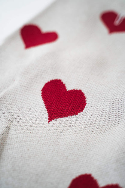 Close-up of a beige dog sweater with red hearts