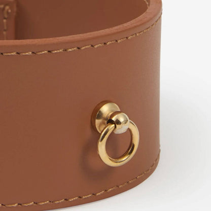 Close-up of the front gold ring on the Branni Pets wide tan leather collar.
Nahaufnahme des vorderen Goldrings am breiten Halsband von Branni Pets.
Gros plan sur l’anneau doré à l’avant du collier large en cuir camel de Branni Pets.
