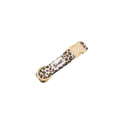 Leopard print dog collar with gold buckle by French Bandit, flat lay on white background – Collier pour chien imprimé léopard avec boucle dorée de la marque French Bandit, présenté à plat sur fond blanc – Hundehalsband mit Leopardenmuster und goldener Schnalle von French Bandit, flach auf weißem Hintergrund präsentiert.