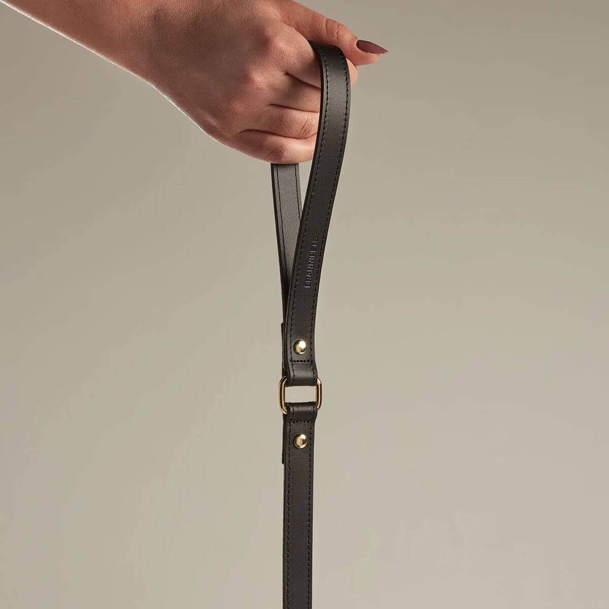 Hand holding the black Branni Pets dog leash loop, highlighting the luxurious feel and secure stitching for comfortable walks. Eine Hand hält die schwarze Branni Pets Hundeleine, die luxuriöses Material und sichere Nähte für angenehme Spaziergänge zeigt. Une main tient la poignée de la laisse noire Branni Pets, soulignant le confort, la sécurité et la qualité du matériau.