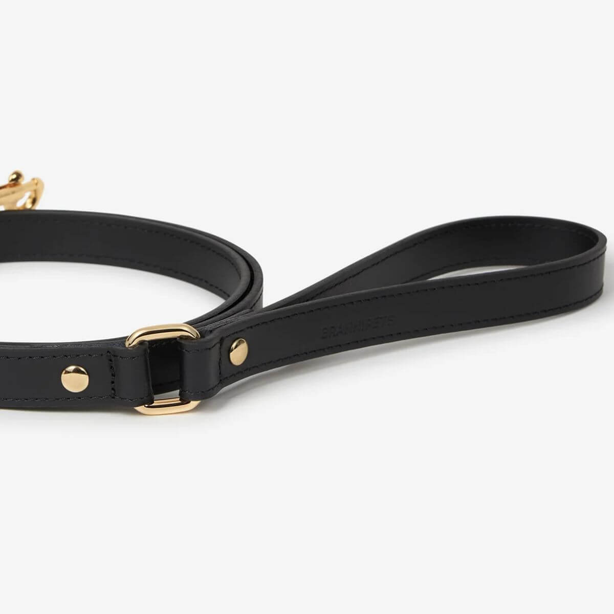 Close-up of the black Branni Pets dog leash handle with gold buckle, highlighting the clean stitching and elegant branding. Nahaufnahme des Griffs der schwarzen Branni Pets Hundeleine mit goldener Schnalle, feine Verarbeitung und stilvolles Branding sichtbar. Gros plan de la poignée de la laisse noire Branni Pets avec boucle dorée, coutures soignées et signature discrète.
