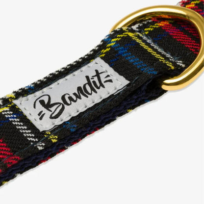 Close-up of the French Bandit dog collar in red tartan with a gold ring and stitched brand label – high-quality and well-crafted. Nahaufnahme des French Bandit Hundehalsbands im roten Tartan-Muster mit goldfarbenem Ring und gesticktem Markenlabel – hochwertig verarbeitet. Gros plan du collier pour chien tartan rouge de French Bandit avec anneau doré et étiquette cousue – finition soignée et artisanale.