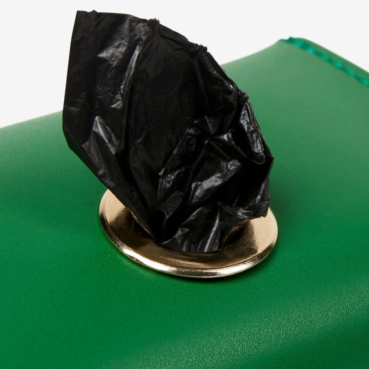 This close-up showcases the premium golden button on a green Branni Pets poop bag holder made from smooth leather. Diese Nahaufnahme zeigt den goldenen Druckknopf des Branni Pets Kotbeutelhalters aus glattem grünem Leder. Ce gros plan présente le bouton-pression doré du porte-sacs à déjections canines Branni Pets en cuir vert lisse.