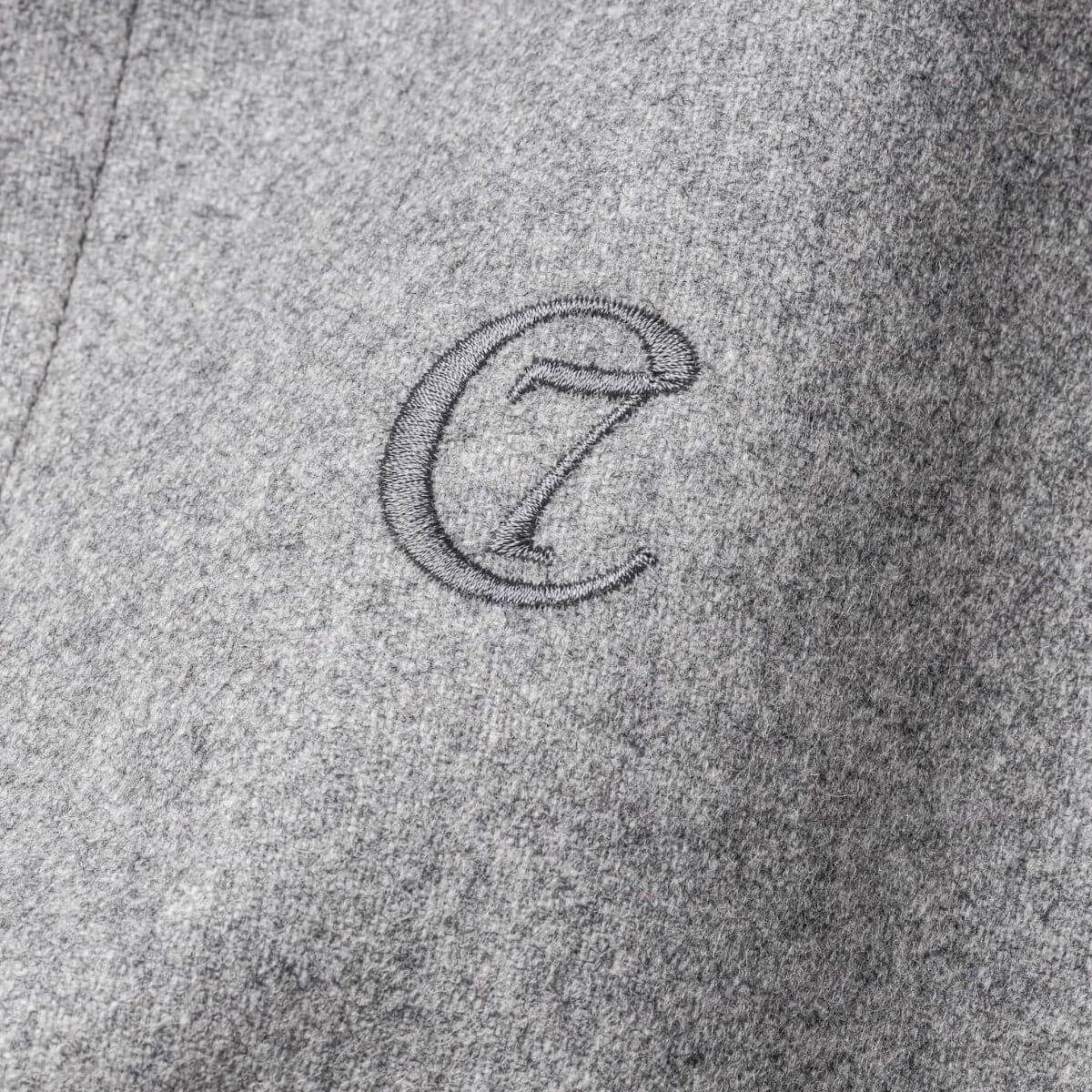 Close-up of embroidered Cloud7 logo on soft grey dog winter coat. | Nahaufnahme des gestickten Cloud7-Logos auf einem weichen grauen Wintermantel für Hunde. | Gros plan du logo brodé Cloud7 sur un manteau d’hiver gris doux pour chien.