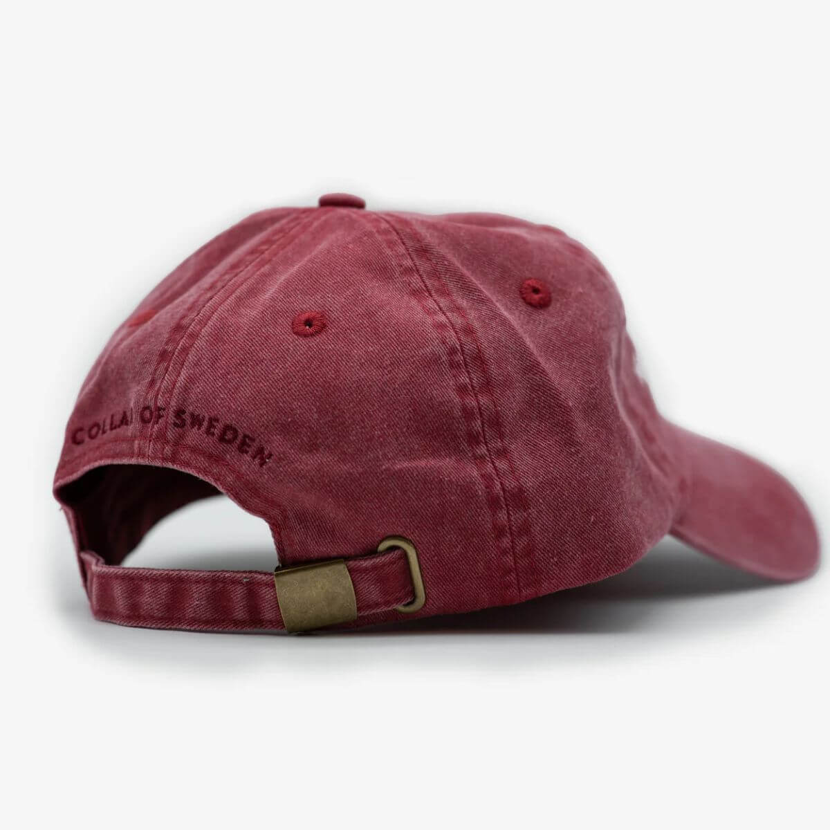 Back of red washed denim cap by Collar of Sweden with adjustable strap and subtle branding. Rückseite der roten verwaschenen Denim-Cap von Collar of Sweden mit verstellbarem Riemen und dezentem Logo. Dos de la casquette en denim rouge délavé de Collar of Sweden avec sangle réglable et logo discret.