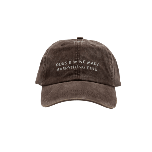 Front view of brown washed denim cap with embroidered slogan "DOGS & WINE MAKE EVERYTHING FINE" by Collar of Sweden. Vorderansicht der verwaschenen braunen Denim-Cap mit gesticktem Slogan "DOGS & WINE MAKE EVERYTHING FINE" von Collar of Sweden. Vue de face de la casquette en denim marron délavé avec slogan brodé "DOGS & WINE MAKE EVERYTHING FINE" de Collar of Sweden.