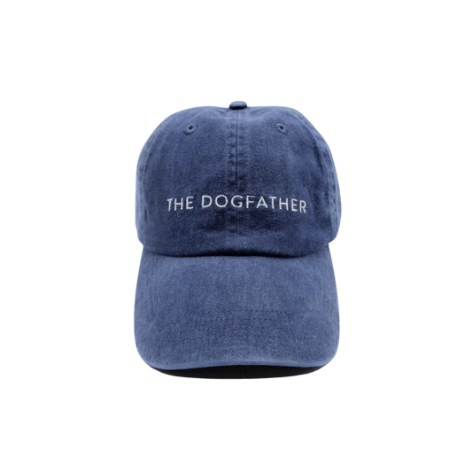 Blue baseball cap with "THE DOGFATHER" embroidery on the front by Collar of Sweden – Casquette bleue avec l'inscription "THE DOGFATHER" brodée à l'avant, signée Collar of Sweden – Blaufarbene Baseballkappe mit „THE DOGFATHER“-Stickerei vorne von Collar of Sweden.